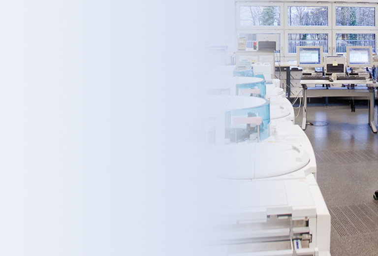 Automatenlabor des medizinisches Labor Bremen mit mehreren weißen Analysegeräten und drei Personen in weißen Laborkitteln, die an Computern arbeiten