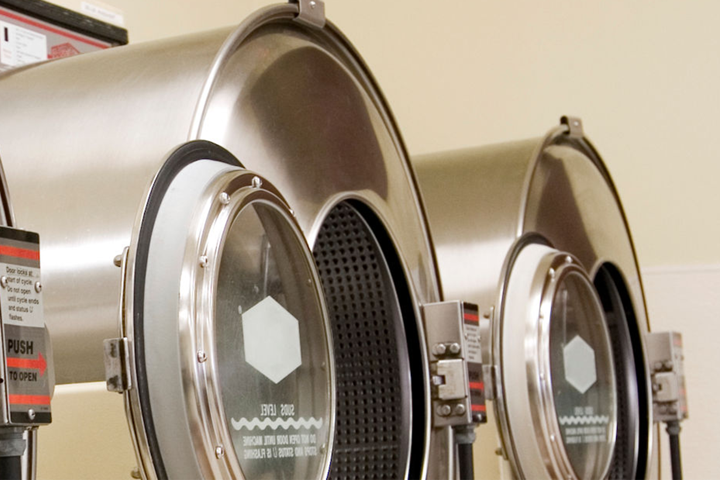 Drei industrielle Waschmaschinen mit runden Türen zur Überprüfung der Desinfektion mit Bioindikatoren