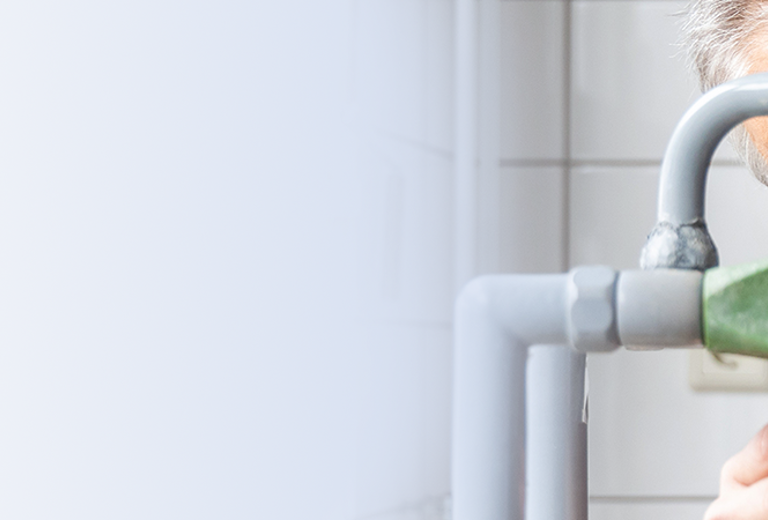 Mann mit Brille füllt im Rahmen mikrobiologischer Wasseruntersuchungen eine Probe aus einem Wasserhahn in ein klares Gefäß ab