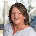 Christine Groß-Stümpke, mit schulterlangen braunen Haaren, trägt ein weißes Oberteil. 