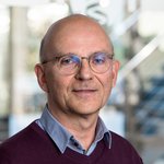 Dr. rer. nat. Hans-Wolfgang Hoppe trägt eine Brille und einen dunkelroten Pullover über einem Hemd. 