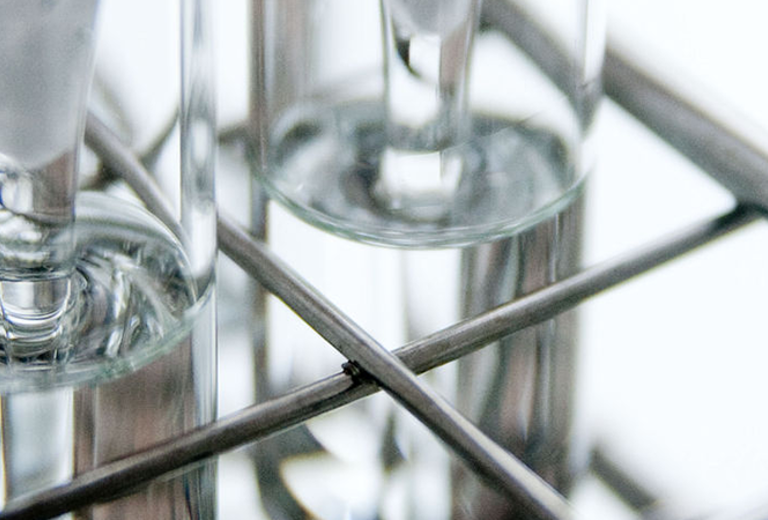 Drei gläserne Sektgläser auf einem Metallgestell, mit langen Stielen und breiten Kelchen.