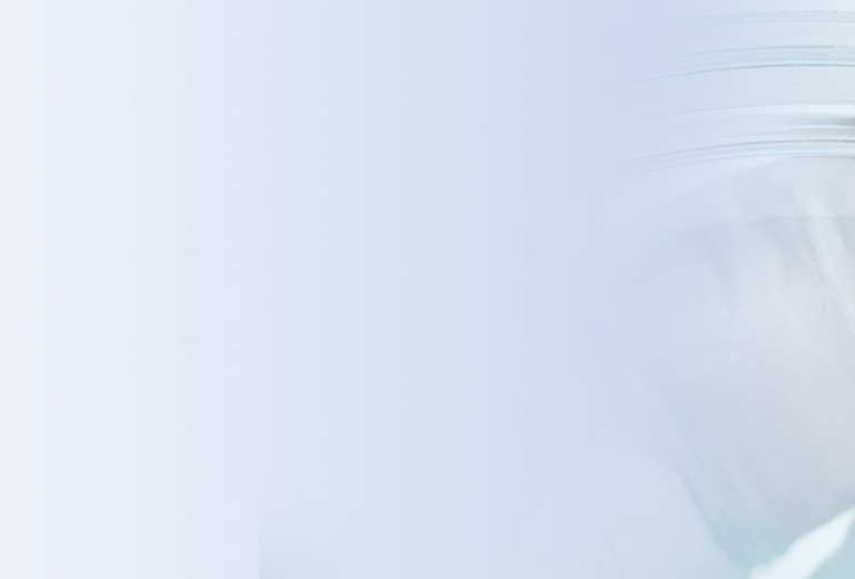 Eine Zecke sitzt in einer Petrischale, die von einer Hand gehalten wird. Die Zecke hat eine ovale Form und ist rotbraun gefärbt.